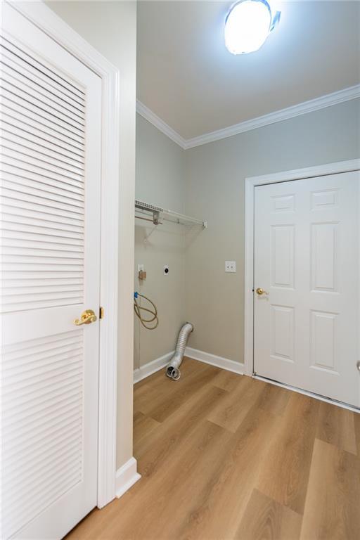 washroom featuring light wood-style flooring, laundry area, baseboards, ornamental molding, and electric dryer hookup