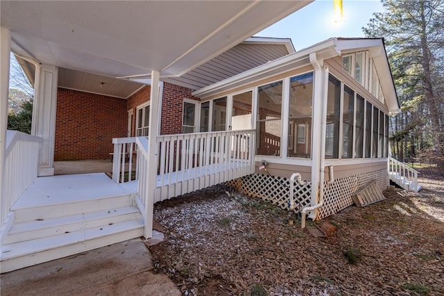 view of side of home featuring brick siding and a sunroom