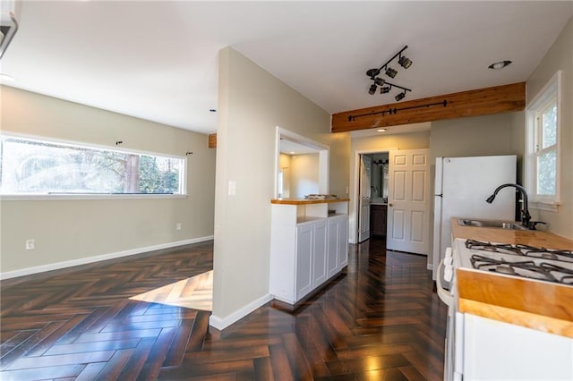 kitchen featuring white gas range oven, baseboards, a sink, and butcher block countertops