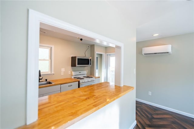 kitchen with white appliances, butcher block countertops, an AC wall unit, a sink, and recessed lighting