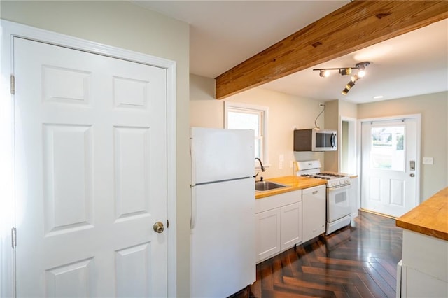 kitchen featuring white appliances, white cabinets, wood counters, a sink, and beam ceiling