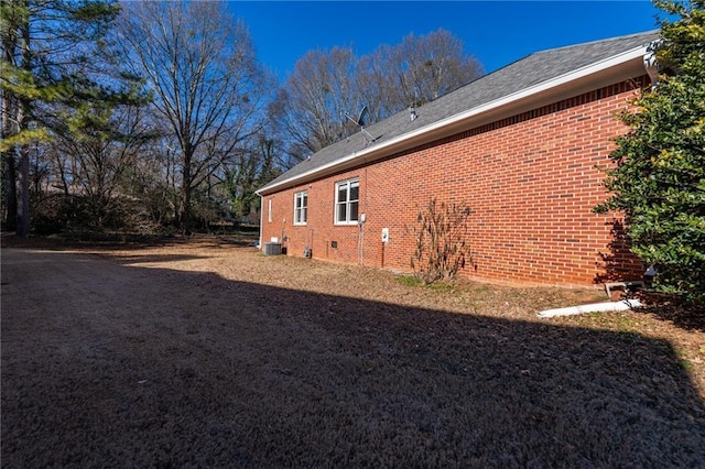 view of side of home featuring crawl space, central air condition unit, and brick siding