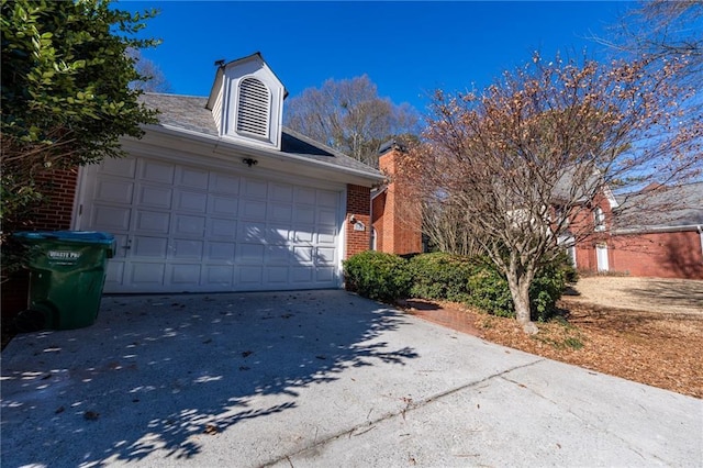 view of side of home featuring a garage, concrete driveway, and brick siding