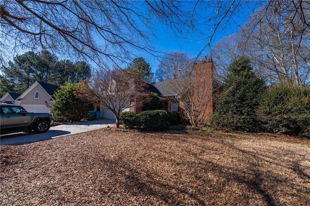 exterior space with a garage, concrete driveway, and a chimney