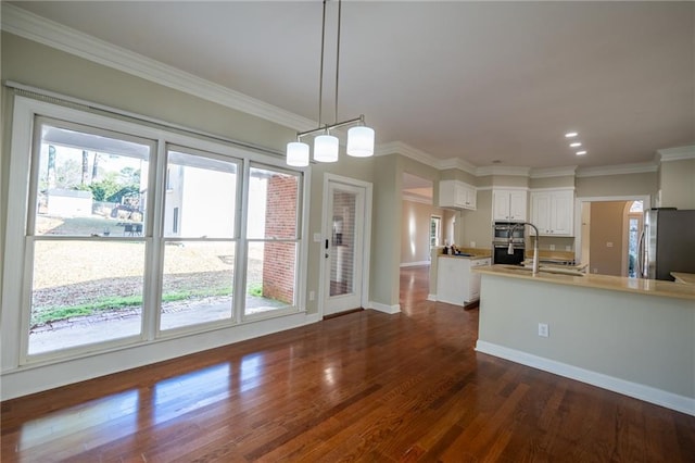 kitchen with white cabinets, dark wood-style flooring, stainless steel appliances, crown molding, and a sink