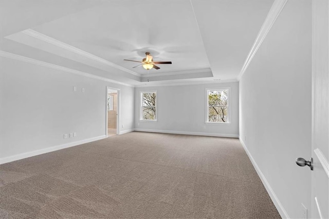 unfurnished room featuring a raised ceiling, ornamental molding, carpet, and ceiling fan