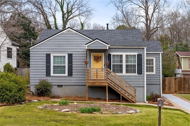 bungalow-style house featuring crawl space, a shingled roof, fence, and a front lawn