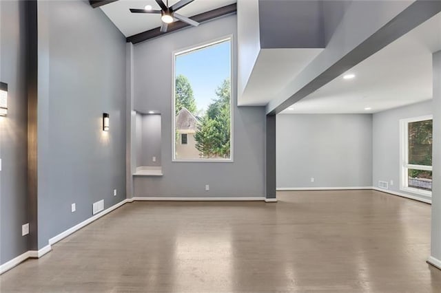 empty room featuring plenty of natural light, baseboards, ceiling fan, and wood finished floors