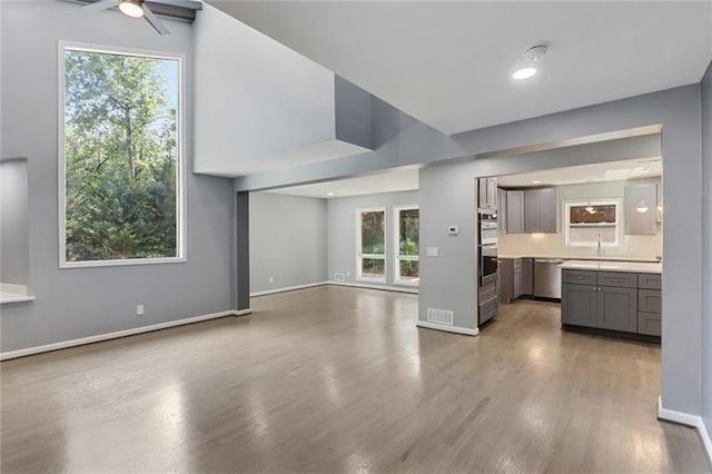 kitchen featuring a ceiling fan, gray cabinets, light countertops, light wood-style floors, and open floor plan