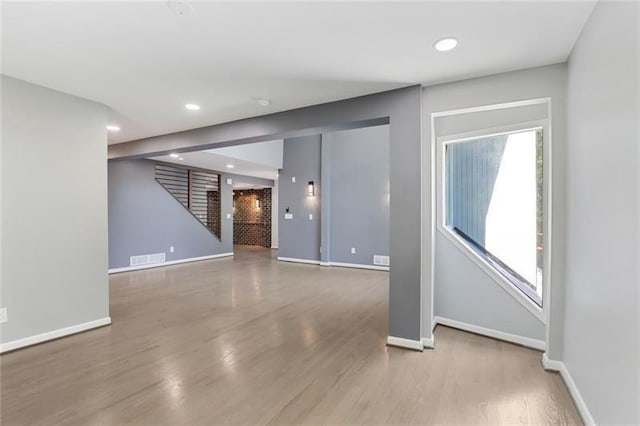 spare room with stairway, visible vents, baseboards, and wood finished floors