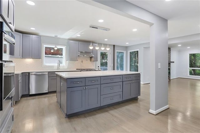 kitchen with backsplash, gray cabinetry, under cabinet range hood, and stainless steel appliances