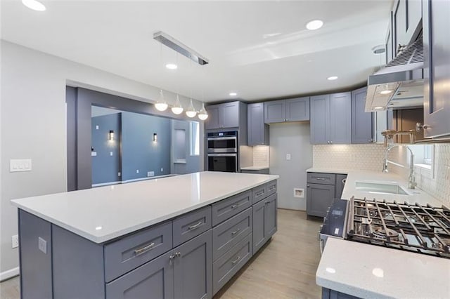 kitchen with gray cabinetry, a sink, double oven, light countertops, and decorative backsplash