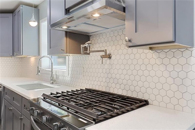 kitchen with range with gas stovetop, a sink, decorative backsplash, light countertops, and exhaust hood