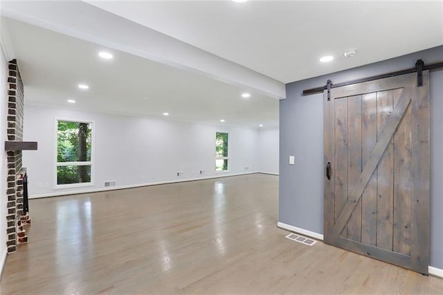 interior space with a barn door, recessed lighting, wood finished floors, and visible vents