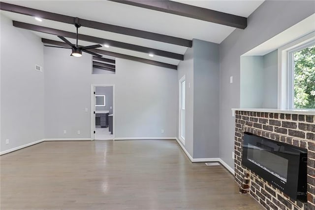 unfurnished living room featuring wood finished floors, baseboards, vaulted ceiling with beams, ceiling fan, and a brick fireplace