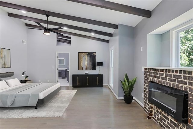 bedroom with wood finished floors, visible vents, baseboards, vaulted ceiling with beams, and a brick fireplace