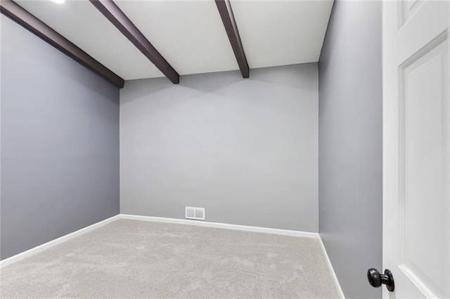 empty room with beam ceiling, carpet flooring, visible vents, and baseboards