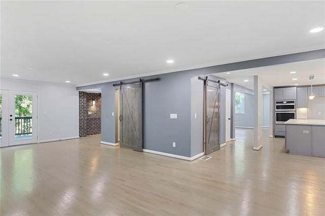 unfurnished living room with light wood finished floors, recessed lighting, and a barn door