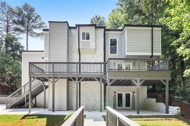 back of house with stairs, french doors, stone siding, a deck, and a patio area