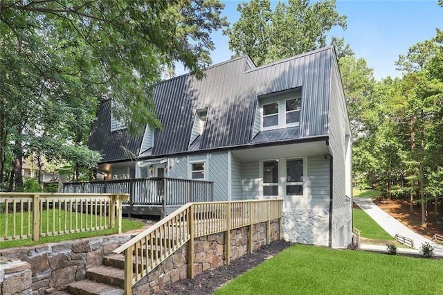 back of house featuring a deck, a gambrel roof, metal roof, and a yard