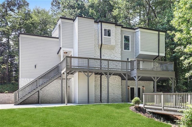 back of house with stairway, a wooden deck, a garage, a yard, and stone siding