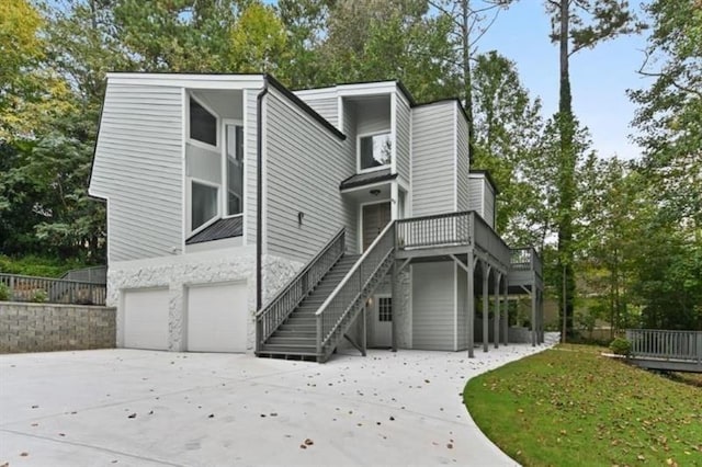 exterior space with an attached garage, a wooden deck, stairs, and driveway