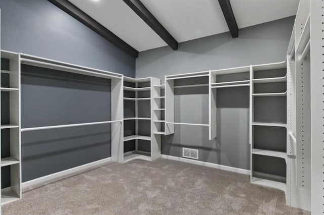 walk in closet with beam ceiling, visible vents, and carpet floors