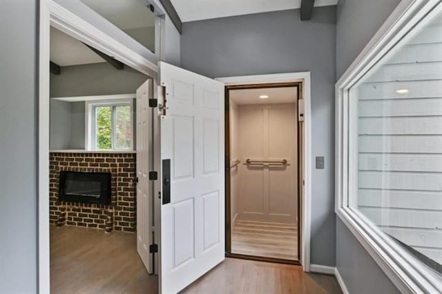 hall with beamed ceiling, baseboards, and wood finished floors