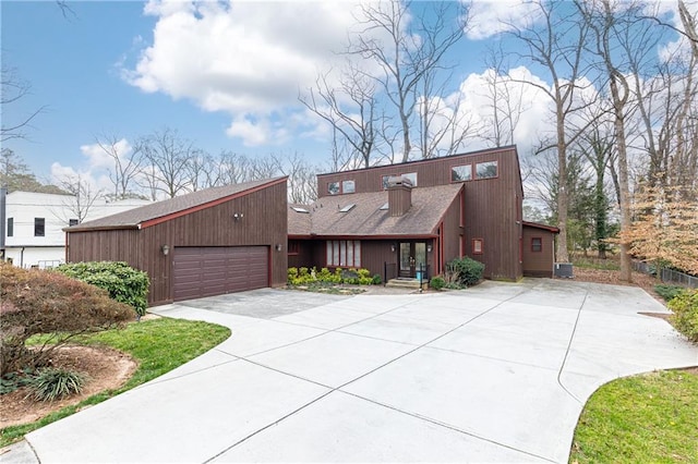 mid-century home with a garage, concrete driveway, and roof with shingles