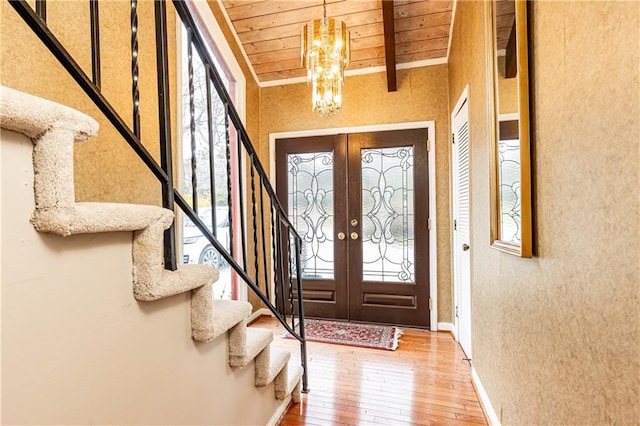 foyer with wooden ceiling, hardwood / wood-style flooring, stairs, a chandelier, and beam ceiling