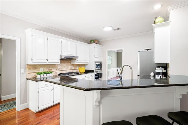 1558 Amberwood Creek Dr NW, Kennesaw, GA 30152 - kitchen with a peninsula, white cabinetry, ornamental molding, tasteful backsplash, and appliances with stainless steel finishes