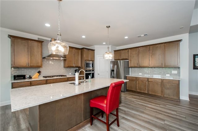 kitchen featuring appliances with stainless steel finishes, a breakfast bar, sink, and a center island with sink