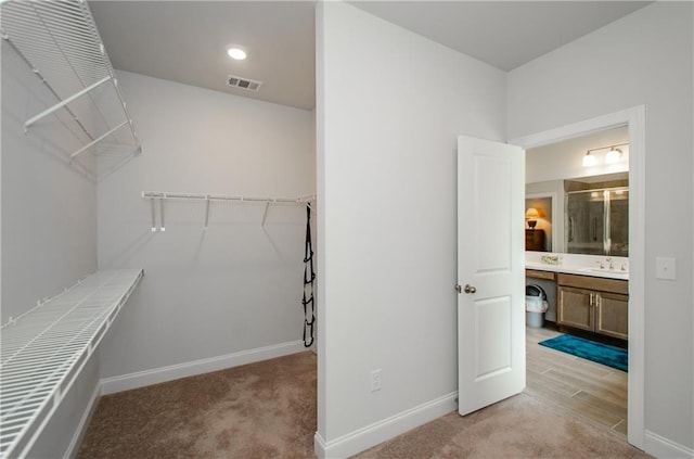 walk in closet with sink and light colored carpet