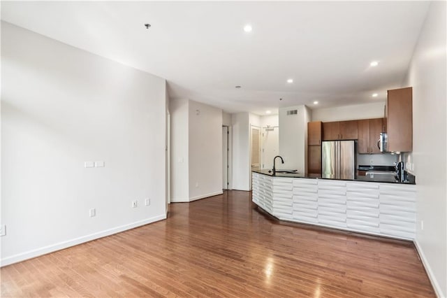 kitchen featuring appliances with stainless steel finishes, hardwood / wood-style floors, kitchen peninsula, and sink