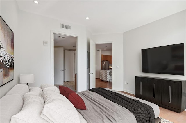 bedroom featuring light hardwood / wood-style flooring and stainless steel fridge