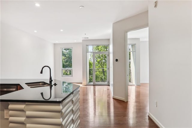 kitchen with an island with sink, sink, and dark hardwood / wood-style flooring