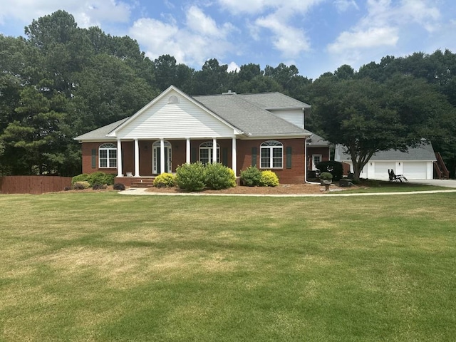 neoclassical home with a front yard, brick siding, fence, and a detached garage