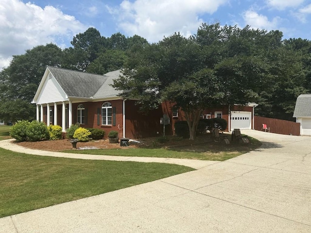 view of front of property with brick siding, fence, driveway, roof with shingles, and a front yard