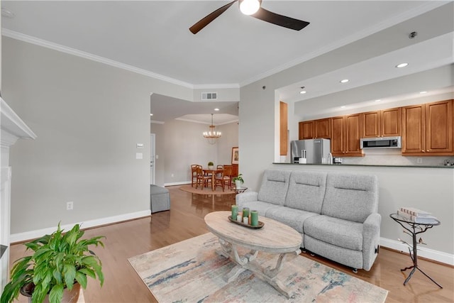 living room featuring ceiling fan with notable chandelier, light hardwood / wood-style floors, and crown molding