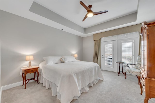 carpeted bedroom featuring a tray ceiling, access to outside, and ceiling fan