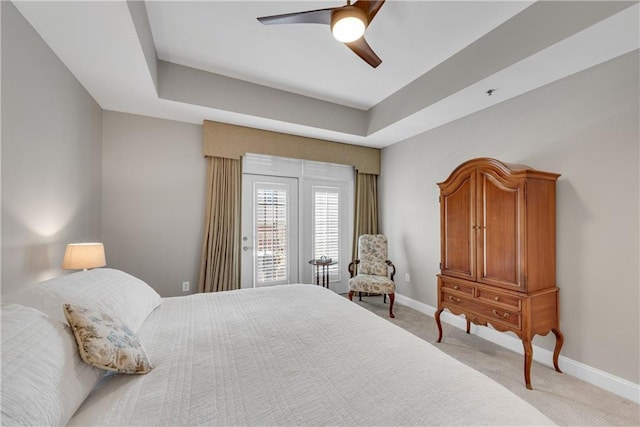 bedroom featuring light carpet, a raised ceiling, access to outside, and ceiling fan