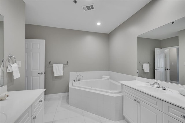 bathroom featuring tiled tub, vanity, and tile patterned floors