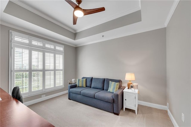 living room with crown molding, a raised ceiling, light carpet, and ceiling fan