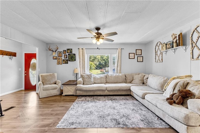 living room featuring ceiling fan, wood-type flooring, and a textured ceiling