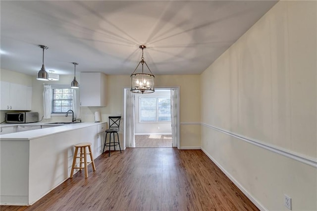 kitchen featuring white cabinets, wood-type flooring, and hanging light fixtures