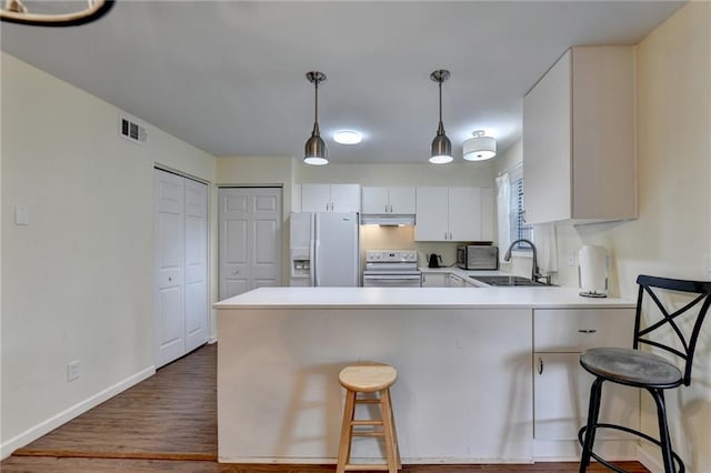 kitchen with white cabinetry, white appliances, sink, and a breakfast bar area