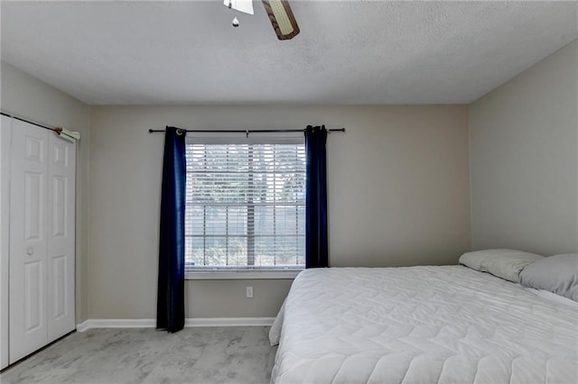 bedroom featuring ceiling fan, light colored carpet, and a textured ceiling