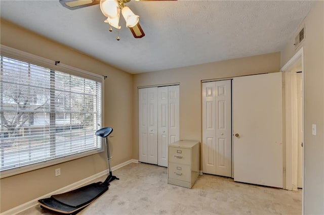 exercise room with ceiling fan and a textured ceiling