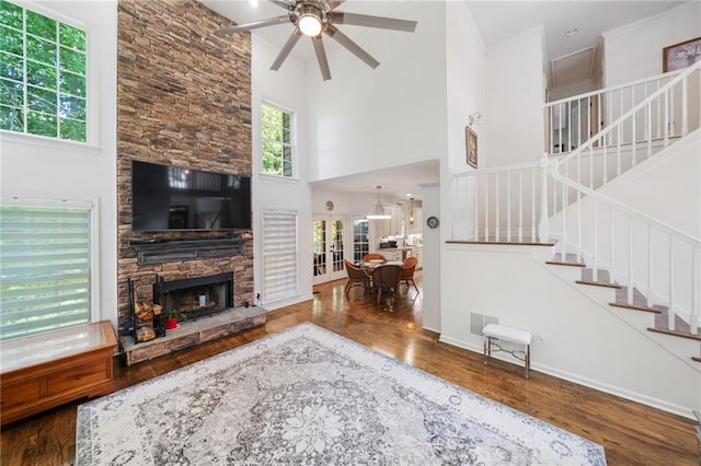 living room with ceiling fan, a fireplace, baseboards, stairs, and dark wood finished floors