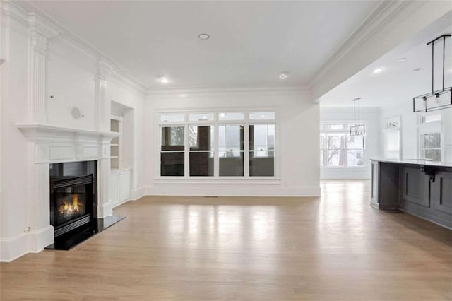 unfurnished living room featuring crown molding, built in features, and light hardwood / wood-style floors